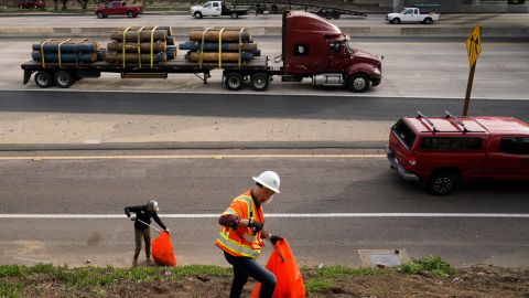 California Gov. Gavin Newsom, left, helps clean a homeless encampment alongside a freeway, Wednesday, Jan. 12, 2022, in San Diego. Newsom is calling for $2 billion to expand access to housing and mental health services for homeless people. (AP Photo/Gregory Bull)