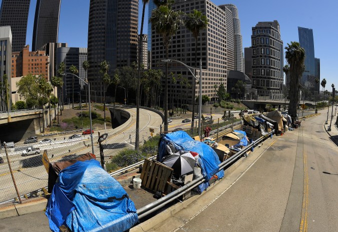 FILE - This May 21, 2020, file photo shows a homeless encampment on Beaudry Avenue as traffic moves along Interstate 110 below during the coronavirus outbreak, in downtown Los Angeles. The leader of a Los Angeles homeless agency announced her resignation Monday, April 25, 2022, amid a dispute with the organization's board over her efforts to increase the minimum pay level for staff. (AP Photo/Mark J. Terrill,File)