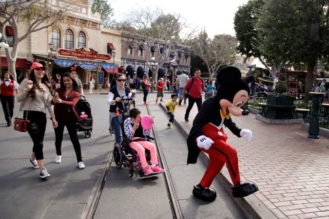 FILE - Visitors follow Mickey Mouse for photos at Disneyland, Jan. 22, 2015, in Anaheim, Calif. Disney is seeking approval from local officials to expand its California theme park offerings over the next four decades. The proposal wouldn't increase the company's geographic footprint in Anaheim, Calif., but would allow for new attractions, for example, on what is currently a large parking lot. (AP Photo/Jae C. Hong, File)