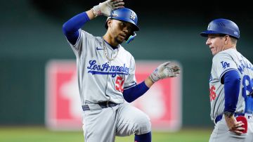 Los Angeles Dodgers' Mookie Betts, left, celebrates his single against the Arizona Diamondbacks as Dodgers first base coach Clayton McCullough looks on during the eighth inning of a baseball game Wednesday, May 1, 2024, in Phoenix. The Dodgers won 8-0. (AP Photo/Ross D. Franklin)