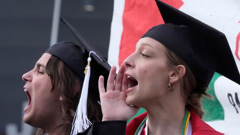 Estudiantes con toga y birrete de graduación se unen a otros manifestantes en la Universidad de Utah
