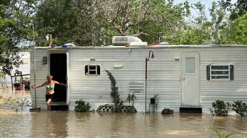 Una mujer sale de una casa móvil rodeada por la inundación causada por el río San Jacinto en un área suburbana cera de Houston, Texas.