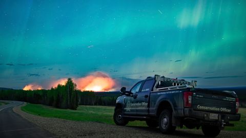 This photo provided by the Ministry of Water, Land and Resource Stewardship shows a wildfire, Aurora Borealis overhead, near Fort Nelson, British Columbia Saturday, May 11, 2024. An intense wildfire could hit a town in western Canada on Monday, based on forecasts of strong winds that have been fueling the out-of-control blaze which has already forced the evacuation of thousands, fire experts and officials warned. (Ministry of Water, Land and Resource Stewardship/The Canadian Press via AP)