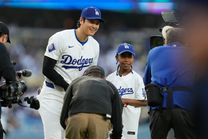 Los Angeles Dodgers designated hitter Shohei Ohtani, center left, greets Albert Lee, center right, who threw out the ceremonial first pitch before a baseball game against the Cincinnati Reds in Los Angeles, Thursday, May 16, 2024. (AP Photo/Ashley Landis)