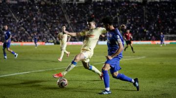 America's Israel Reyes, left, and Cruz Azul's Ignacio Rivero compete for the ball during the Mexican soccer league final first leg match at the Sports City stadium in Mexico City, Thursday, May 23, 2024. (AP Photo/Eduardo Verdugo)
