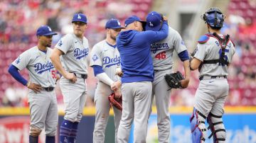 Los Angeles Dodgers pitcher Yohan Ramírez (46) is embraced by manager Dave Roberts, third from right, after he hit Cincinnati Reds' Stuart Fairchild with a throw during the eighth inning of a baseball game Sunday, May 26, 2024, in Cincinnati. (AP Photo/Jeff Dean)