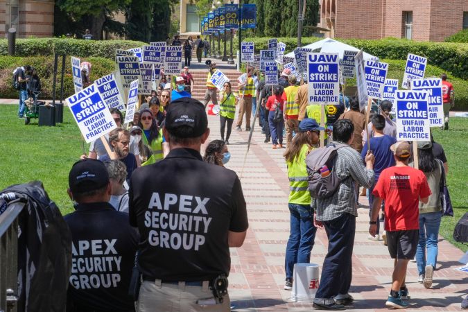 Apex security group guards keep an eye on UCLA workers, students and supporters picket at Royce Quad in the University of California, Los Angeles, UCLA campus Tuesday, May, 28, 2024, The UAW union representing student workers of the University of California have escalated a labor standoff to include three campuses. (AP Photo/Damian Dovarganes)