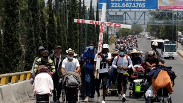 Inmigrantes avanzan por Puebla bajo una cruz de madera con las palabras “Resucitó, Cristo".