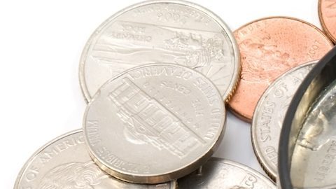 Lupa encima de una colección de monedas.