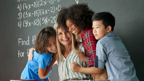 Niños felices y diversos, estudiantes multiculturales de secundaria abrazando a una maestra apreciando y agradeciendo a la educadora en el aula