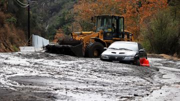 A bulldozer operator begins to clear a car trapped in a deep debris flow that covered parts of Topanga Canyon Boulevard near the village of Topanga west of Los Angeles, Tuesday, Jan. 9, 2017. Multiple people were killed and homes were swept from their foundations as mud and debris from wildfire-scarred hillsides flowed through neighborhoods and onto a key Southern California highway Tuesday during a powerful winter storm that dropped record rain across the state. (AP Photo/Reed Saxon)