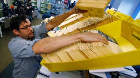 El coordinador de operaciones electorales de la División Electoral de Denver carga las boletas anticipadas en una máquina clasificadora en la sede electoral.