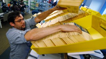 El coordinador de operaciones electorales de la División Electoral de Denver carga las boletas anticipadas en una máquina clasificadora en la sede electoral.