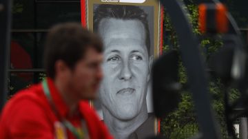 A Ferrari team crew member drives a forklift past a poster of the seven-time F1 champion Michael Schumacher of Germany on display at the paddock of the Shanghai International Circuit ahead of the Chinese Formula One Grand Prix in Shanghai, China, Thursday, April 11, 2019. (AP Photo/Andy Wong)