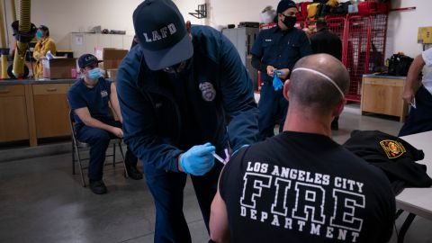 FILE - In this Jan. 27, 2021, file photo, firefighter Adam Brandos, right, receives his second dose of the COVID-19 vaccine from Michael Perez at a fire station in Los Angeles. The resurgence of COVID-19 this summer and the national debate over vaccine requirements have created a fraught situation for the nation's first responders, who are dying in larger numbers but pushing back against mandates. (AP Photo/Jae C. Hong, File)