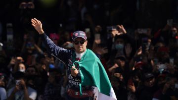 Mexican Formula One Red Bull driver Sergio "Checo" Perez waves as he holds his nation's flag after an exhibition race along Paseo de la Reforma ahead of this weekend's Mexico Grand Prix in Mexico City, Wednesday, Nov. 3, 2021. (AP Photo/Fernando Llano)