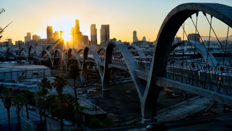 The sun sets over downtown Los Angeles behind the Sixth Street Bridge, a viaduct connecting the downtown Arts District with the historic Boyle Heights neighborhood, in Los Angeles during opening ceremonies for on Saturday, July 9, 2022. (AP Photo/Richard Vogel)