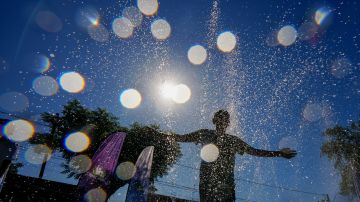 A youth cools off at the "Parque de Agua" public water park on a hot summer day in Santiago, Chile, Wednesday, Jan. 31, 2024. Dozens of public water parks like this are set up across the city during the summer to help residents cool off. (AP Photo/Esteban Felix)