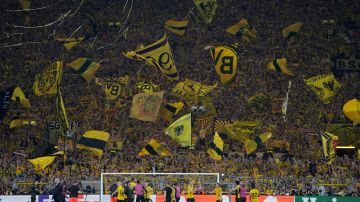 Dortmund supporters wave flags after the Champions League semifinal first leg soccer match between Borussia Dortmund and Paris Saint-Germain at the Signal-Iduna Park stadium in Dortmund, Germany, Wednesday, May 1, 2024. (AP Photo/Matthias Schrader)