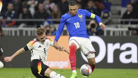 FILE - Germany's Joshua Kimmich, left, kicks the ball ahead of France's Kylian Mbappe during an international friendly soccer match between France and Germany at the Groupama stadium in Decines, near Lyon, central France, Saturday, March 23, 2024. France boasts one of the European Championship’s strongest attacks but it could be offset by a vulnerable defense and a dearth of leadership. While France looks solid in midfield and has Kylian Mbappé with Antoine Griezmann in attack, the defense could be a weak point. (AP Photo/Laurent Cipriani, File)