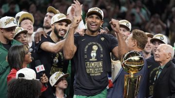 Boston Celtics center Al Horford, center, and forward Jayson Tatum, center left, celebrates with teammates near the Larry O'Brien Championship Trophy after the team won the NBA basketball championship with a Game 5 victory over the Dallas Mavericks, Monday, June 17, 2024, in Boston. (AP Photo/Charles Krupa)