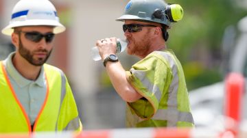 Un trabajador de mantenimiento bebe agua para aliviar el sofocante calor en una calle de Boston.