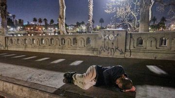 Un hombre sin hogar duerme en una acera del Parque McArthur en Los Ángeles.