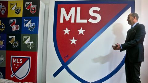 Don garber, comisionado de la MLS junto al logo de la liga y de algunos equipos.