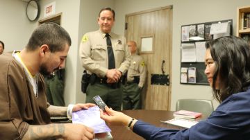 Sergio Aloma (atrás), asistente del alguacil del connado de Los Angeles observa al recluso latino leer un cuento que seria grabado con su voz para su hijo, como regalo en el Día del Padre.