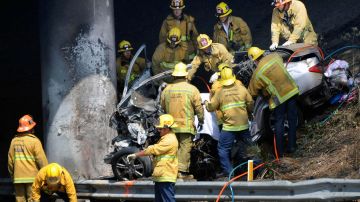 Los Angeles fire fighters remove a driver and passengers from a car that collided into a pillar on the Interstate 10 Freeway near downtown Los Angeles on Sunday July 6,2008. The car burst into flames and two men and two women in the car died. The cause of the crash was not immediately known. (AP Photo/Gene Blevins)