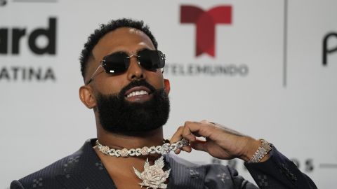 American rapper Eladio Carrion shows off his necklace as he poses for photographers on the blue carpet at the Latin Billboard Awards, in Coral Gables, Fla., Thursday, Oct. 5, 2023. (AP Photo/Rebecca Blackwell)