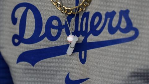 Wearing a bat-and-ball necklace, Los Angeles Dodgers' Mookie Betts sits in the dugout before the team's baseball game against the St. Louis Cardinals Friday, March 29, 2024, in Los Angeles. (AP Photo/Jae C. Hong)