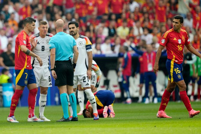 El árbitro inglés Anthony Taylor hablando con los jugadores de la selección alemana Ilkay Gündogan y Toni Kroos durante un momento del partido ante España.