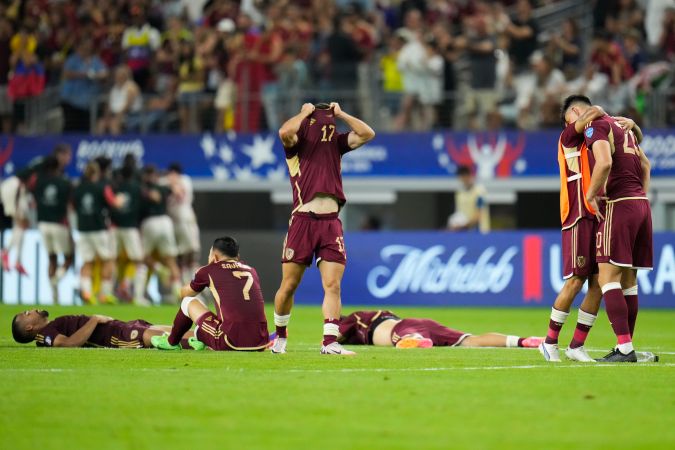 Los jugadores de la Selección de Venezuela lamentando la derrota sufrida ante los canadienses que celebraban en el fondo.