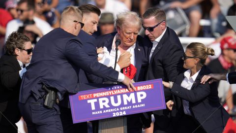 Donald Trump es ayudado por elementos del servicio secreto para desalojar la escena del presunto tiroteo en un evento en Butler, Pennsylvania.