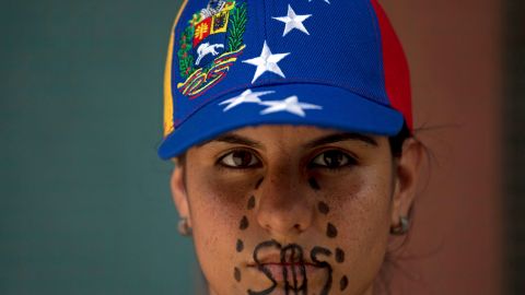 A woman wearing a cap representing Venezuela's national flag, the SOS distress signal marked across her lips and painted black tears streaming down her face, looks into the camera during a demonstration in Caracas, Venezuela, Saturday, March 8, 2014. Venezuelans returned to the streets for the "empty pots march" to highlight growing frustration with shortages of some everyday items. In Caracas, the march was scheduled to end at the country's Food Ministry, but the evening before Caracas' mayor announced that he had not authorized the march. (AP Photo/Fernando Llano)