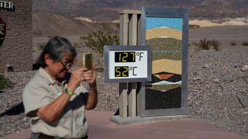People visit a thermometer at the Furnace Creek Visitor Center, Thursday, Sept. 1, 2022, in Death Valley National Park, Calif. The thermometer is not official but is a popular photo spot. (AP Photo/John Locher)