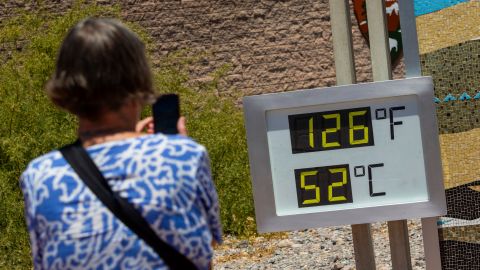 A woman takes a photo of a thermostat reading 126 degrees Fahrenheit and 52 degrees Celsius at the Furnace Creek Visitors Center in Death Valley National Park, Calif., Sunday, July 7, 2024. Forecasters say a heat wave could break previous records across the U.S., including in Death Valley. (AP Photo/Ty ONeil)