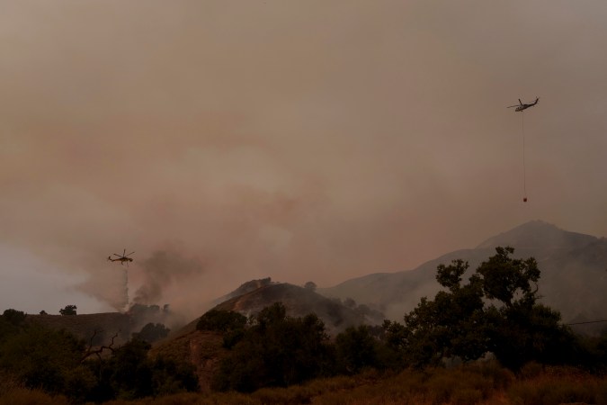 Helicopters drop water on flames from the advancing Lake Fire in Los Olivos, Calif., Saturday, July 6, 2024. (AP Photo/Eric Thayer)