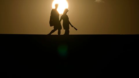 FILE - People walk along a trail as the sun sets, July 16, 2023, in Death Valley National Park, Calif. Across the U.S., many people are living through one of the most brutal summers of their lives and reckoning with the idea that climate change is only going to make matters worse in the coming decades. (AP Photo/John Locher, File)