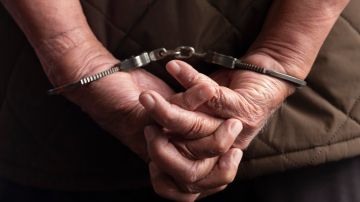 Former Guatemalan army commanders Benedicto Lucas Garcia stands with his hands handcuffed as he is escorted to a courtroom in Guatemala City, Monday, Nov. 25, 2019. Lucas Garcia and other army commanders are accused of steering the military campaign against the Ixil Maya communities between 1978 and 1982 during the country's civil war. (AP Photo/Moises Castillo)