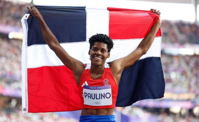 La dominicana Marileidy Paulino posando con la bandera de su país después de imponerse con autoridad en la final de los 400 metros femeninos del atletismo de los Juegos Olímpicos París 2024.
