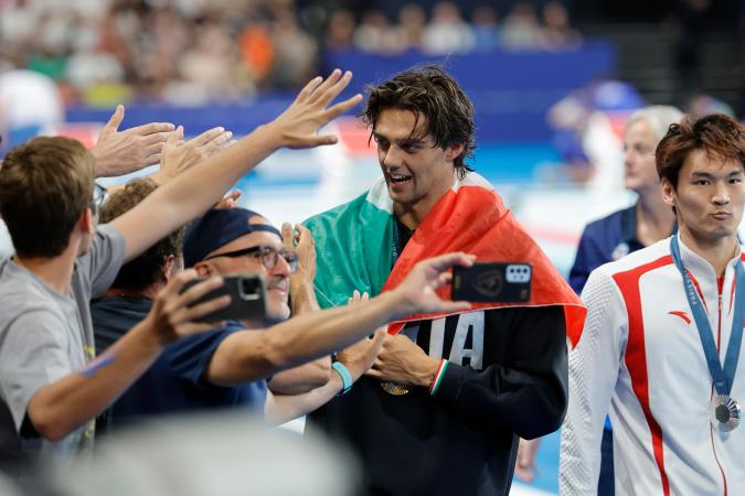 El italiano Thomas Ceccon saludando a los aficionados después de su conquista en los 100 metros espalda de la natación de París 2024.
