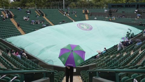 A court steward stands under an umbrella on an outside court as rain delays the start of play at the Wimbledon tennis championships in London, Saturday, July 6, 2024. (AP Photo/Alberto Pezzali)