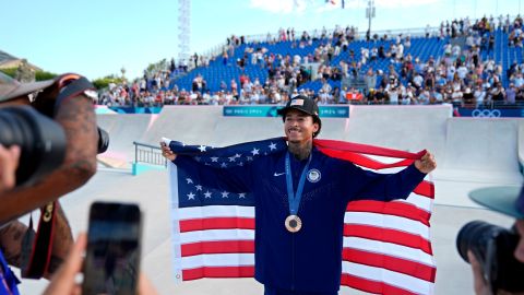 Nyjah Huston posando con su medalla de bronce y con la bandera de Estados Unidos después de su participación en el skateboarding de los Juegos Olímpicos París 2024.