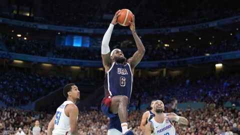 United States' LeBron James, center, goes up for a dunk as Puerto Rico's Tremont Waters, left, and Puerto Rico's Jose Alvarado defend during a men's basketball game at the 2024 Summer Olympics, Saturday, Aug. 3, 2024, in Villeneuve-d'Ascq, France. (AP Photo/Michael Conroy)