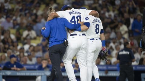 Los Angeles Dodgers relief pitcher Brusdar Graterol (48) is helped getting out of a baseball game against the Philadelphia Phillies due to an apparent injury in Los Angeles, Tuesday, Aug. 6, 2024. (AP Photo/Kyusung Gong)