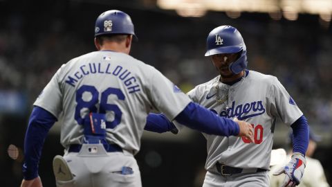 Los Angeles Dodgers' Mookie Betts, right, is congratulated by first base coach Clayton McCullough, left, after hitting an RBI single during the seventh inning of a baseball game against the Milwaukee Brewers, Monday, Aug. 12, 2024, in Milwaukee. (AP Photo/Aaron Gash)