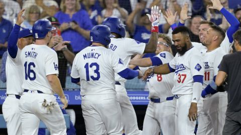 Los Angeles Dodgers Jason Heyward, back center, is congratulated by teammates at the dugout after hitting a pinch hit three-run home run in the eighth inning of a baseball game against the Seattle Mariners, Tuesday, Aug. 20, 2024, in Los Angeles. (AP Photo/Jayne-Kamin-Oncea)