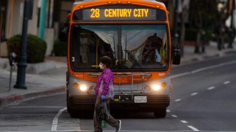 A pedestrian wears a face mask and gloves as she walks in the Chinatown neighborhood of Los Angeles on Thursday, April 2, 2020, during the coronavirus outbreak. (AP Photo/Damian Dovarganes)